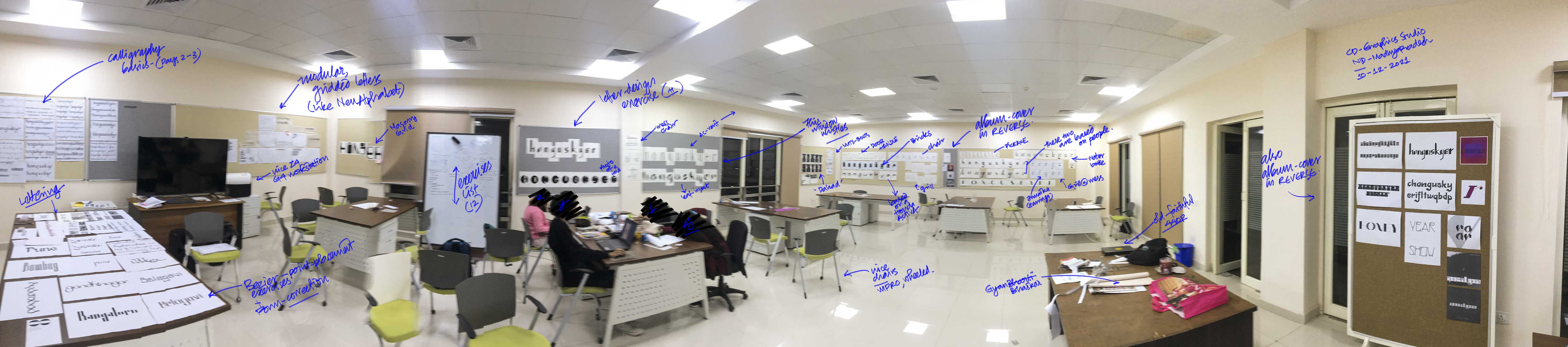 A panoramic image of the second year CD graphics studio at NID Bhopal, showing work displayed on the softboards and tables. The work is from typography-1 and there are four students in the studio, working late-ish in the night. 